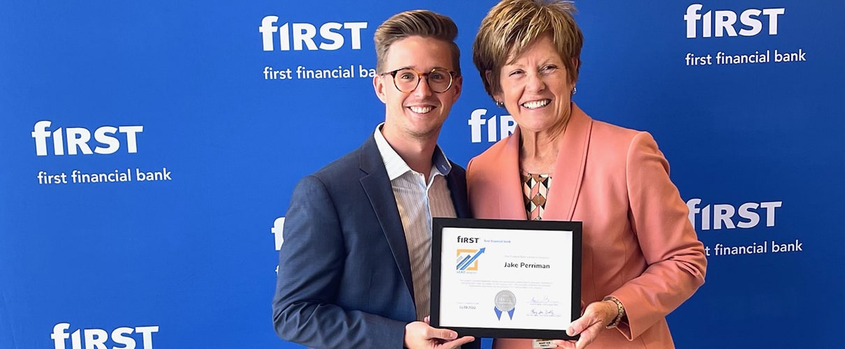 First Financial associate accepting an award while another bank associate takes her picture