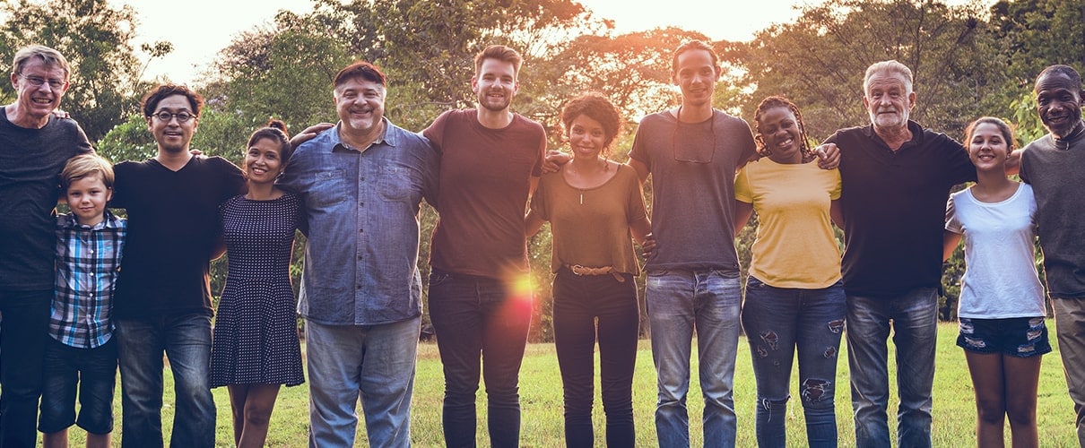 Twelve people standing arm in arm and smiling.