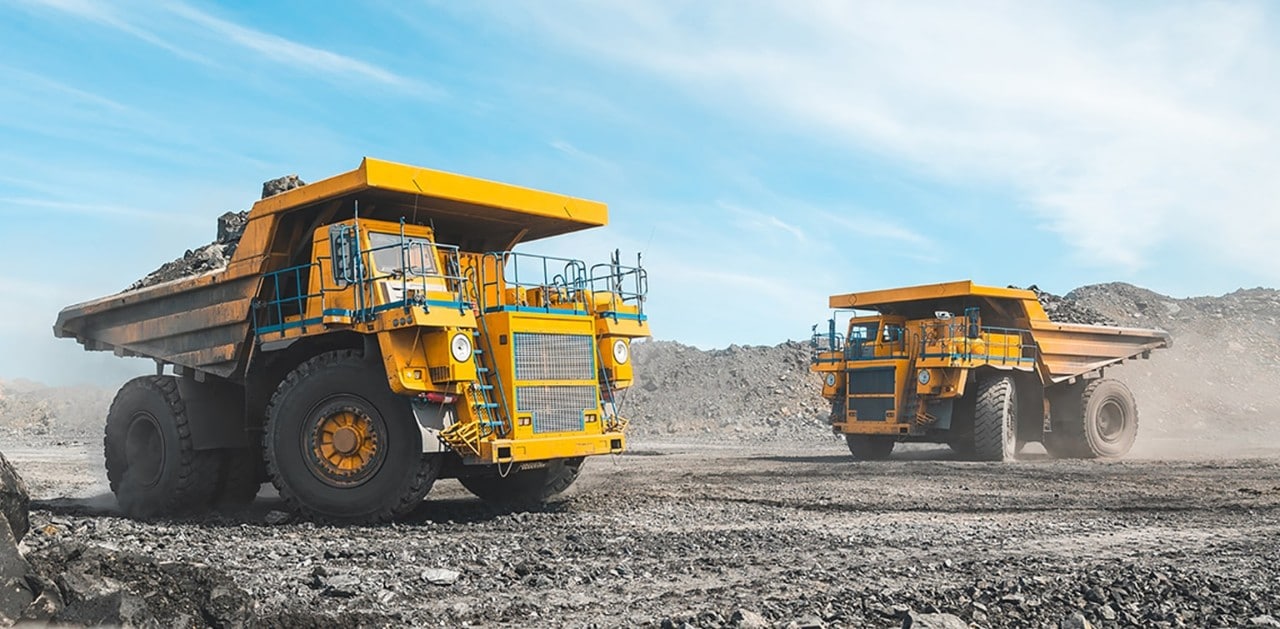 Large construction trucks driving on rocky surface