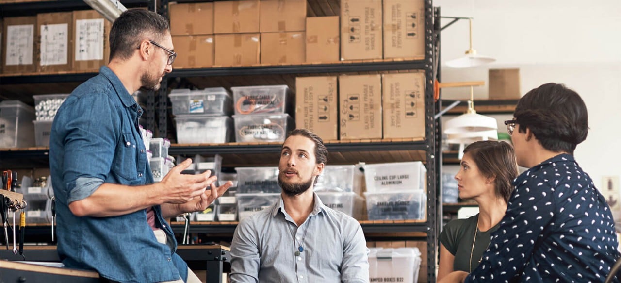 Four colleagues conversing in a warehouse