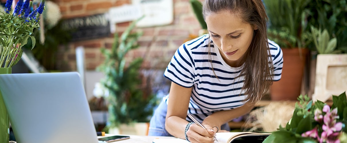 Female florist shop owner working on finances next to open laptop