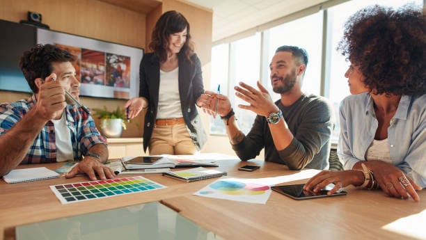 A group of coworkers have a discussion in a meeting room