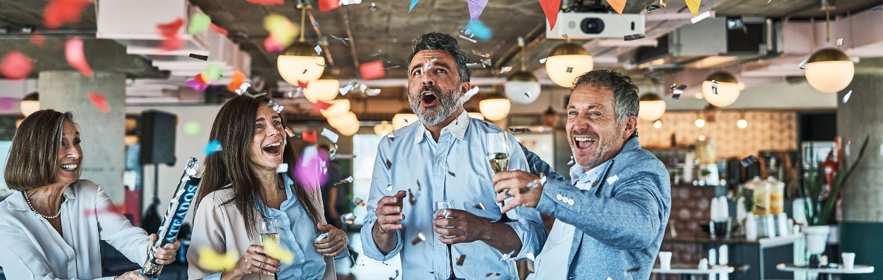 Four colleagues celebrating with confetti and champagne