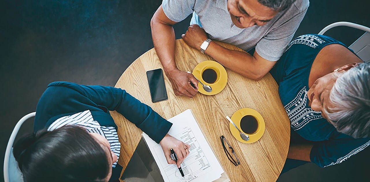 Couple sitting at small round table with advisor