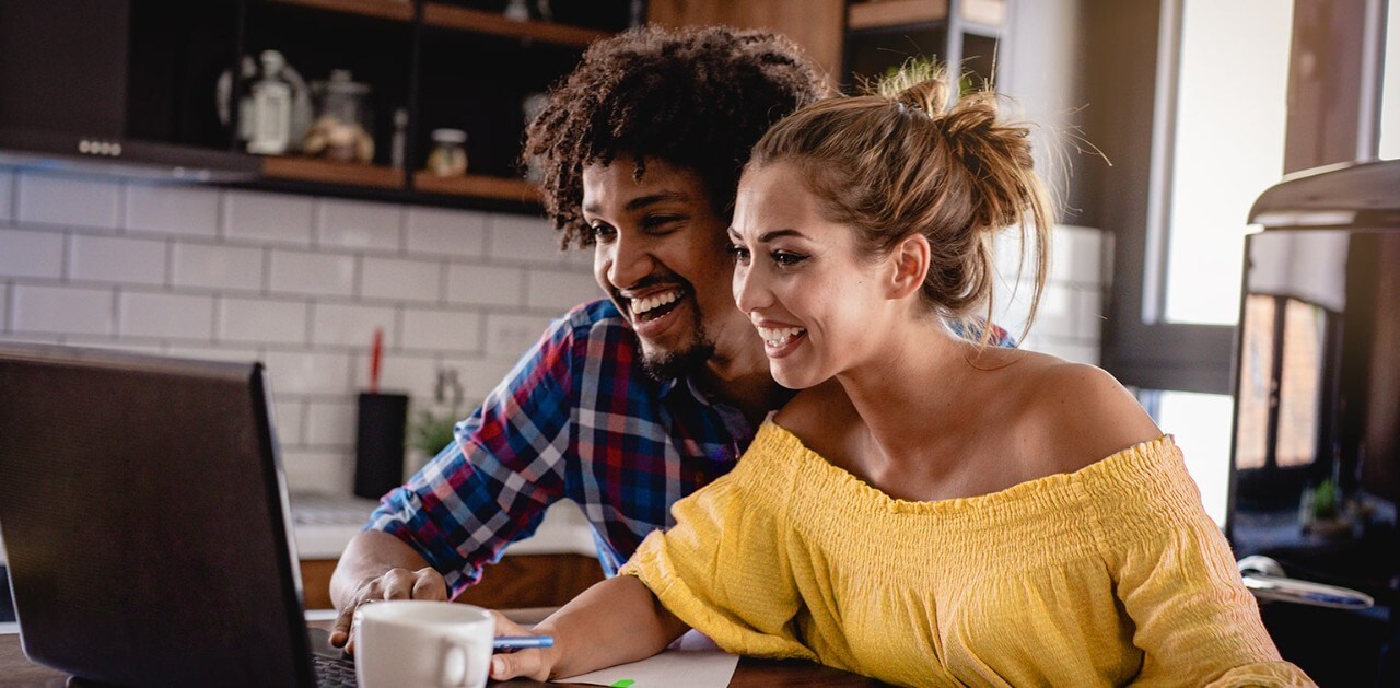 Multiracial couple at table looking at laptop