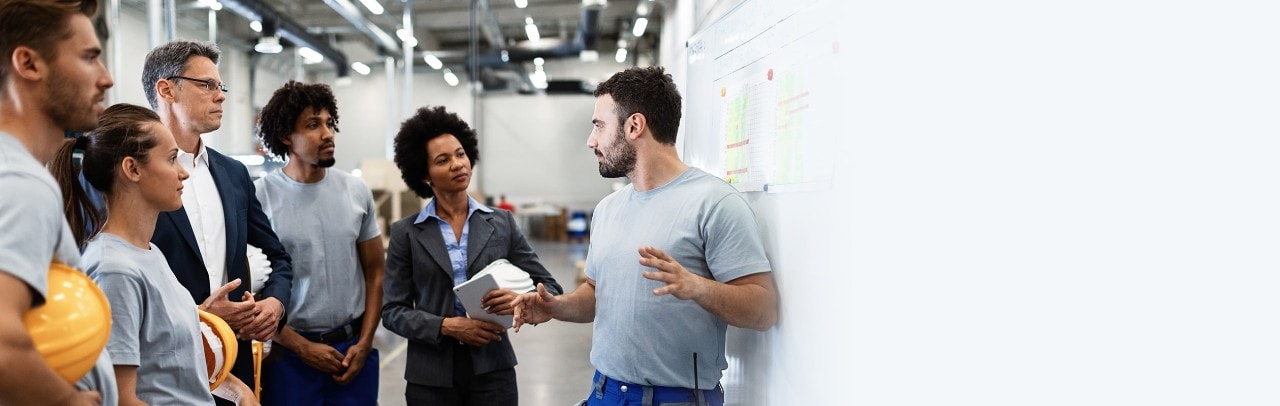 Young factory worker holding presentation about production development to company managers and his coworkers