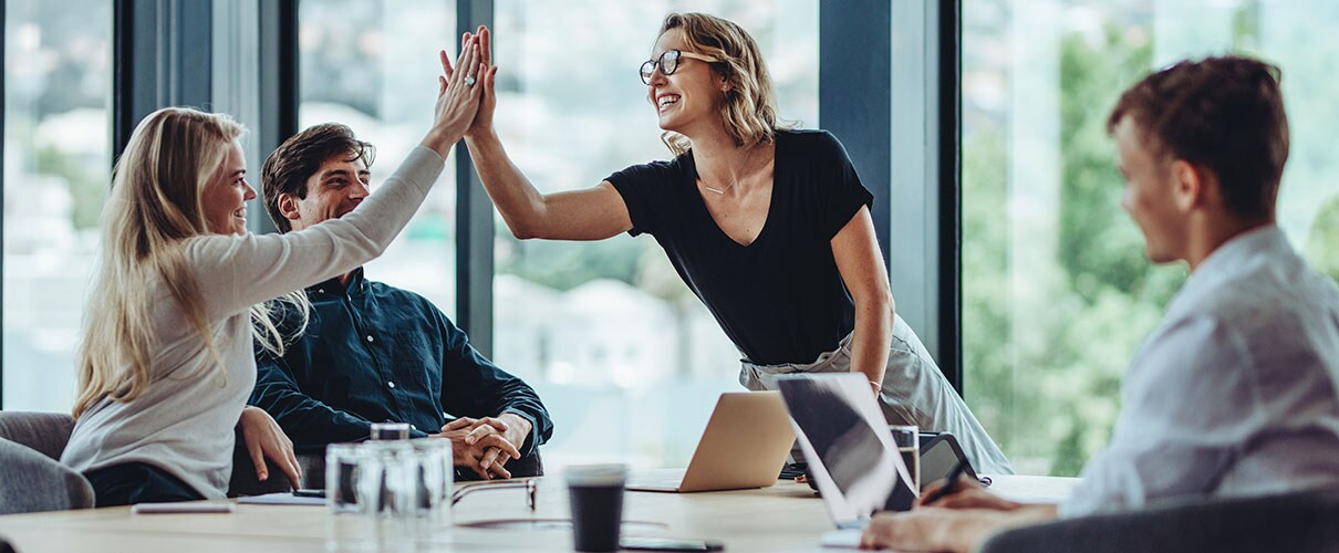 Colleagues high-fiving in a conference room