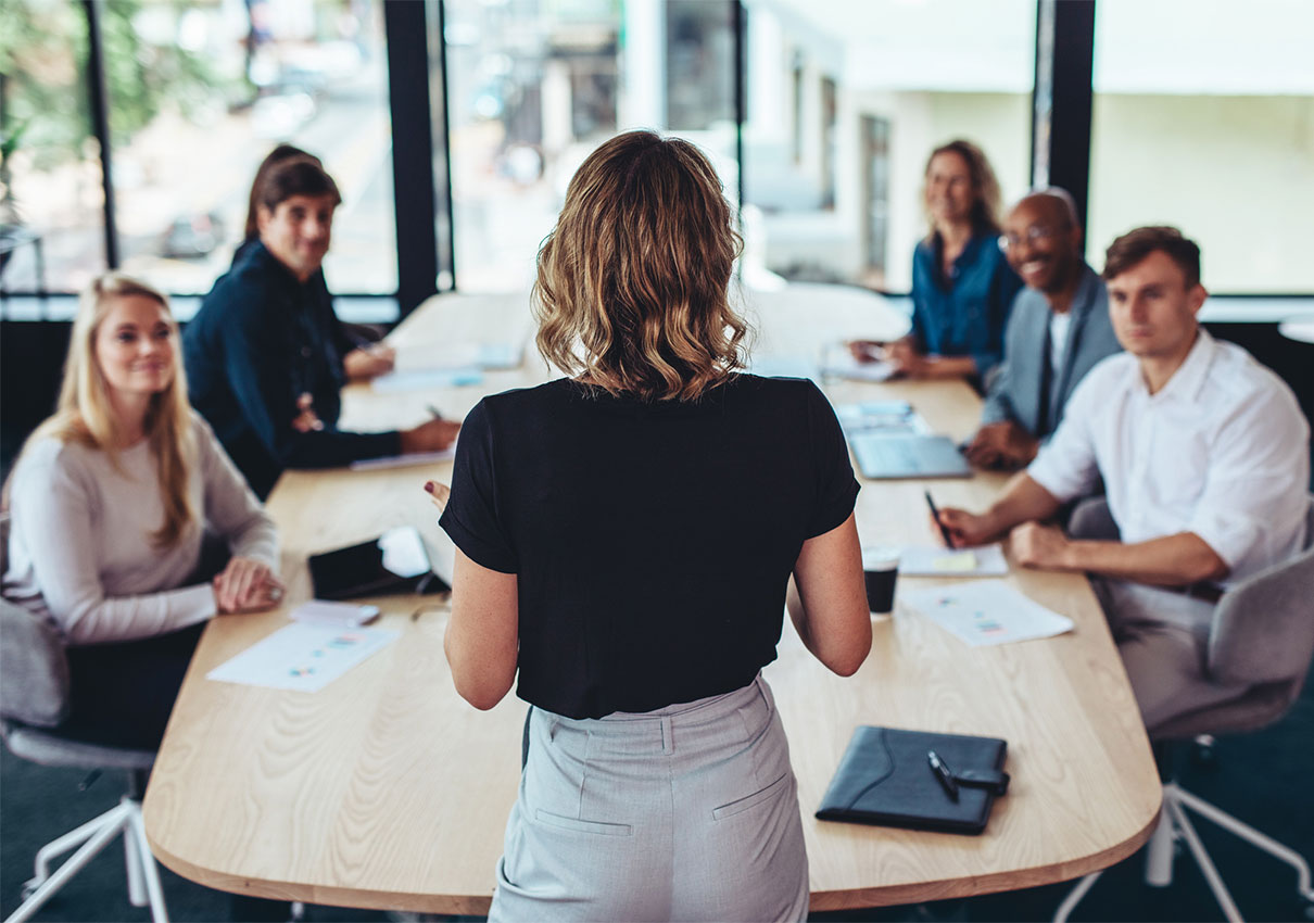 Colleagues gathered around a conference table listening to a presentation