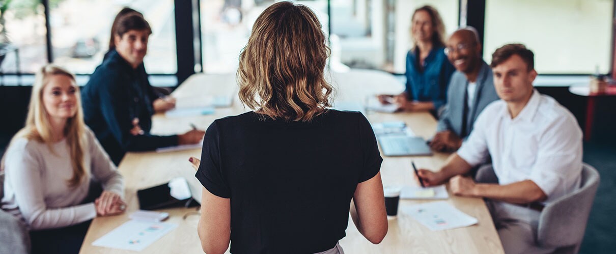 Colleagues gathered around a conference table listening to a presentation