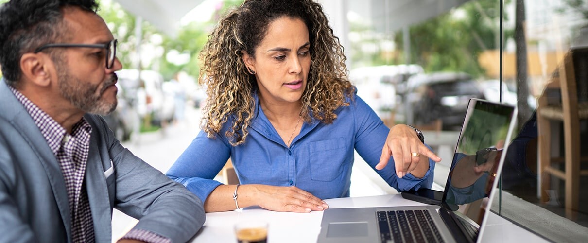 Two business people working on a laptop in a cafe