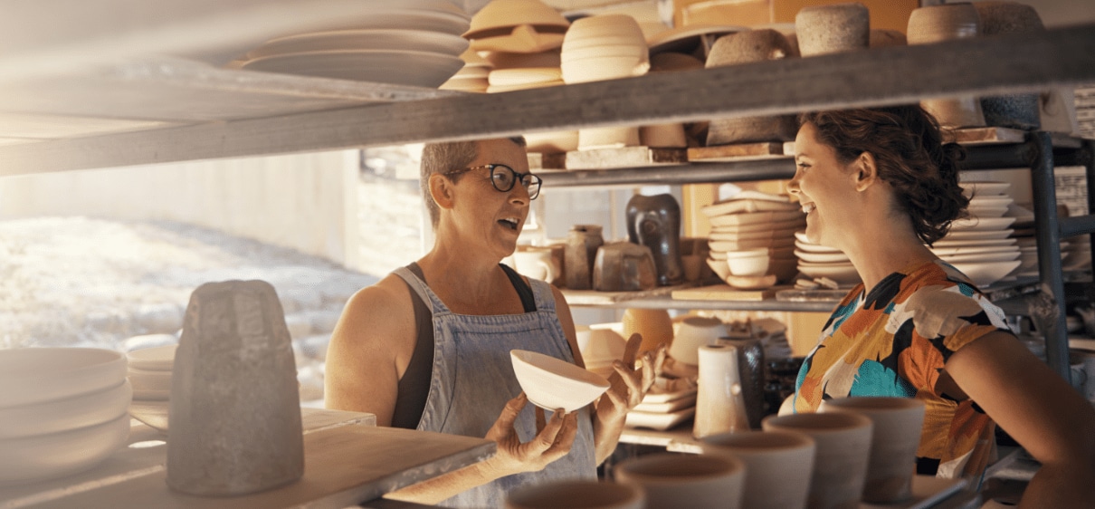 Female business owner speaking with female banker in pottery studio