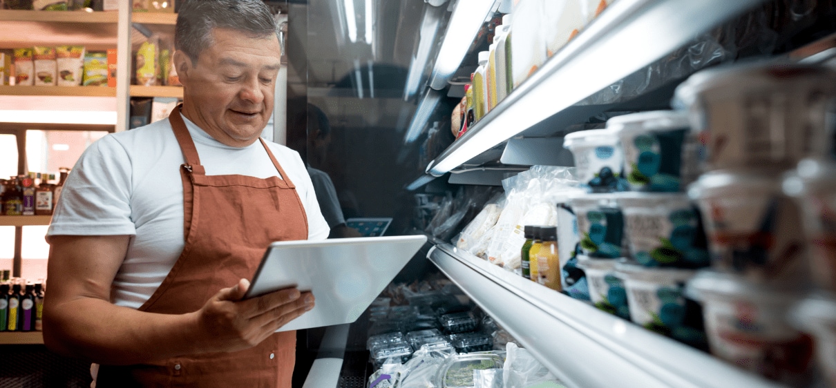 Food store owner holding tablet and reviewing inventory