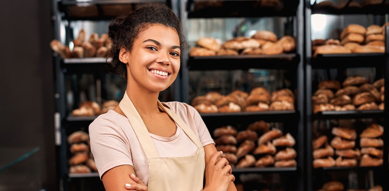 African-American bakery owner standing in front of racks of bread