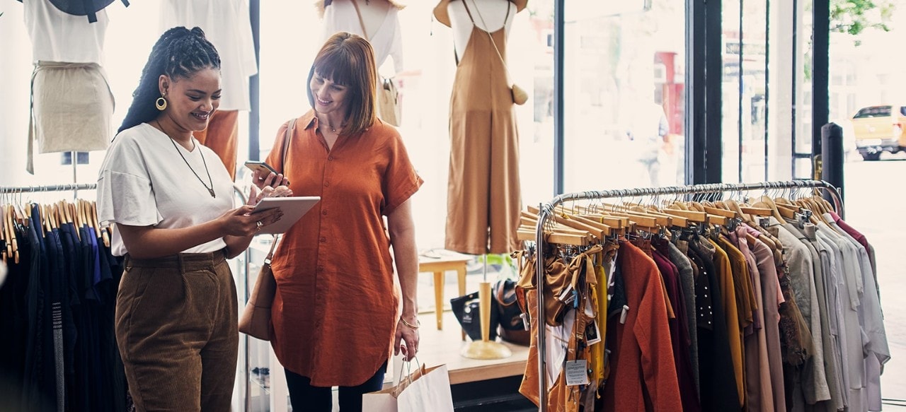 Shot of a shop assistant using a digital tablet while assisting a customer in a boutique