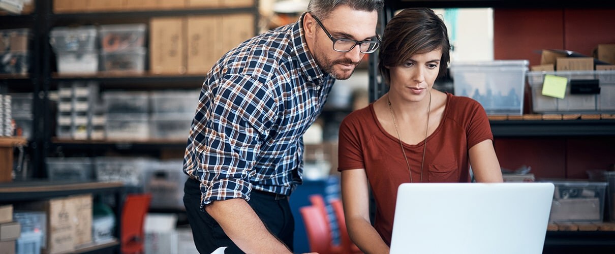 Business partners in warehouse using laptop