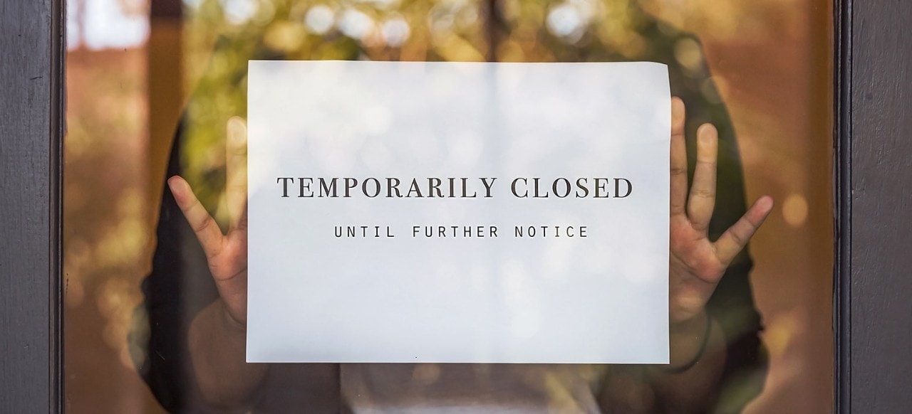 Business owner hanging “temporarily closed” sign on door