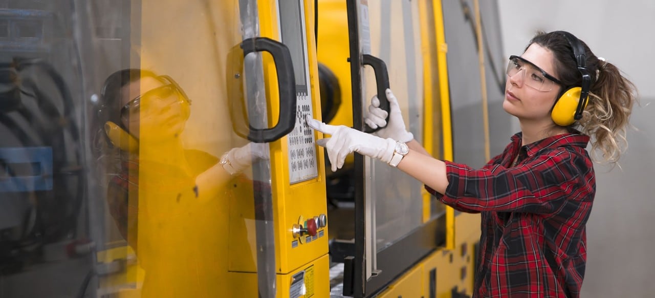 Female manufacturing employee working with large equipment