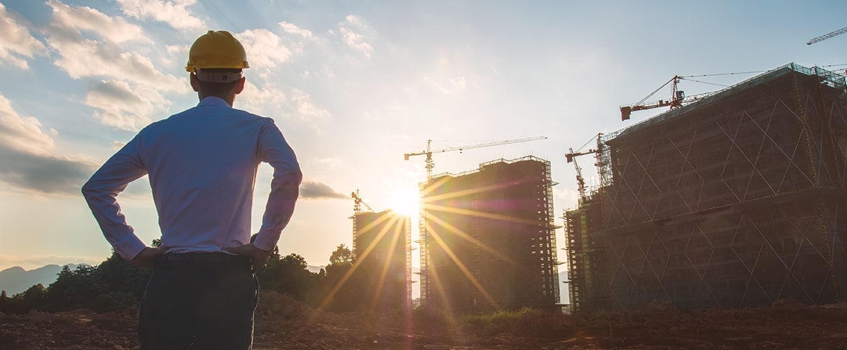 Man in a yellow hard hat looking at construction site