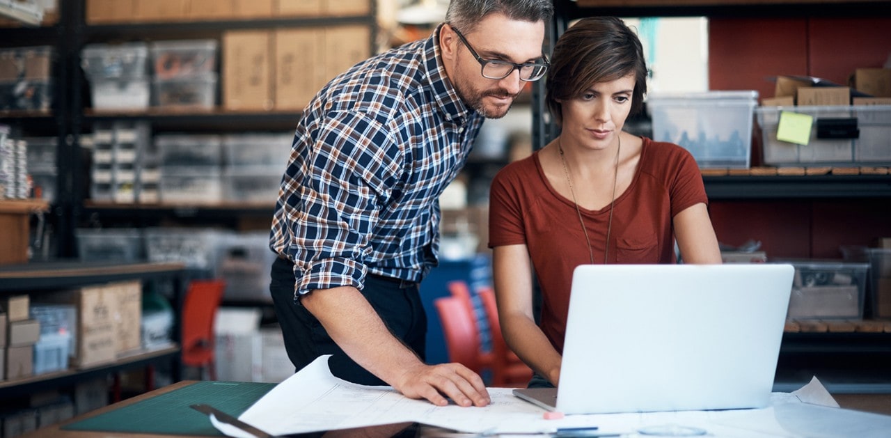 Business partners in warehouse using laptop