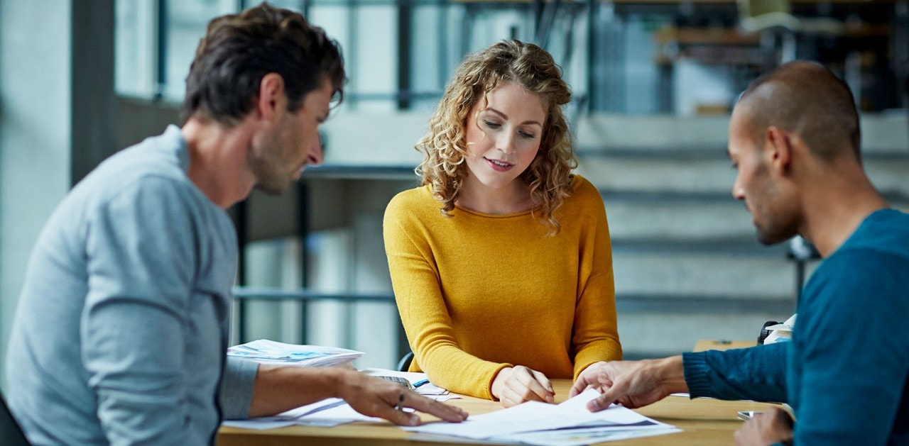 Three coworkers reviewing documents at a table