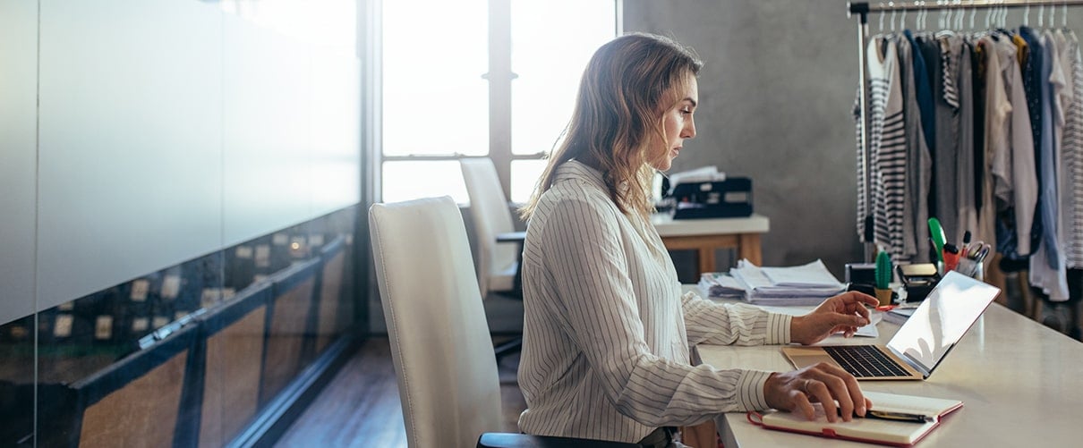 Female clothing retailer logging inventory on laptop