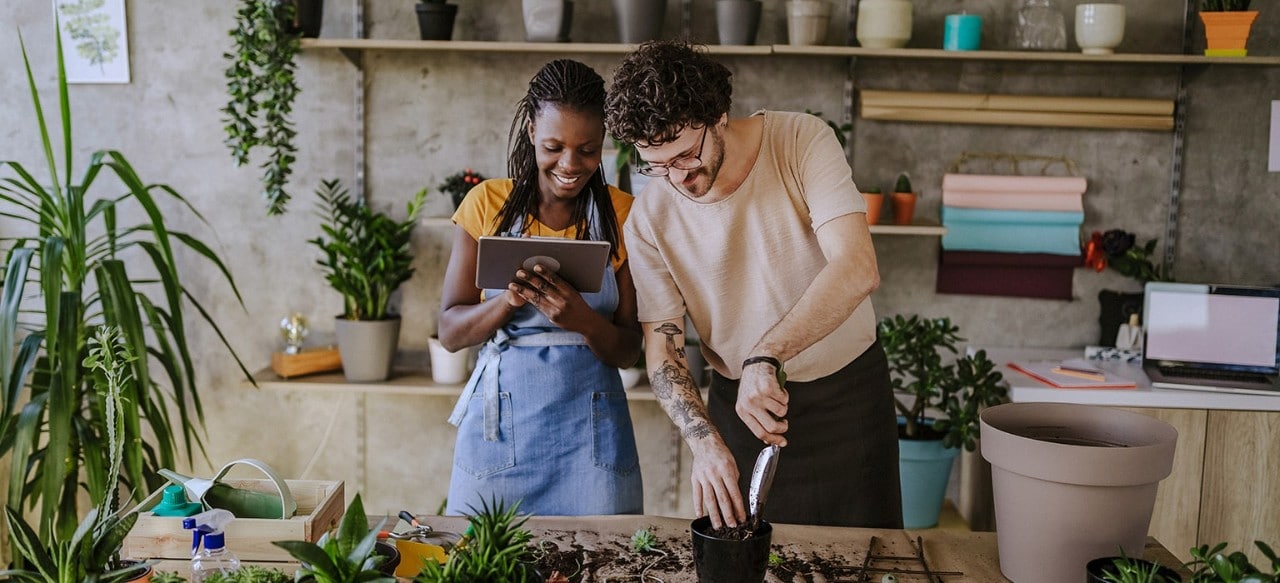 Multi-racial flower shop owners working on table and planting flowers