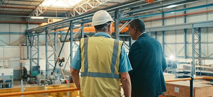 Foreman and executive conversing in warehouse