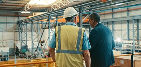 Foreman and executive conversing in warehouse