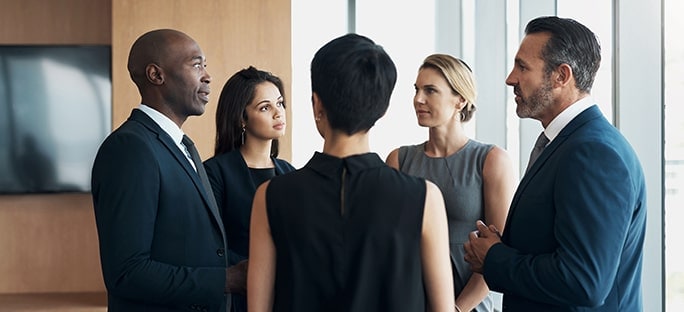 Five colleagues in business attire conversing in conference room