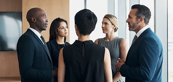 Five colleagues in business attire conversing in conference room