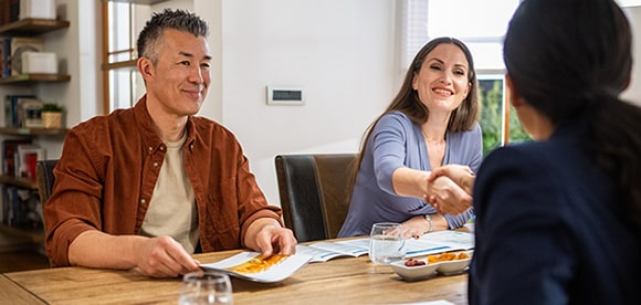Middle-aged couple shaking hands with financial advisor