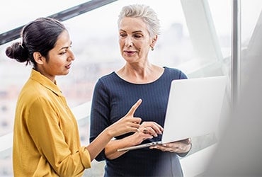 Two businesswomen reviewing information on a laptop