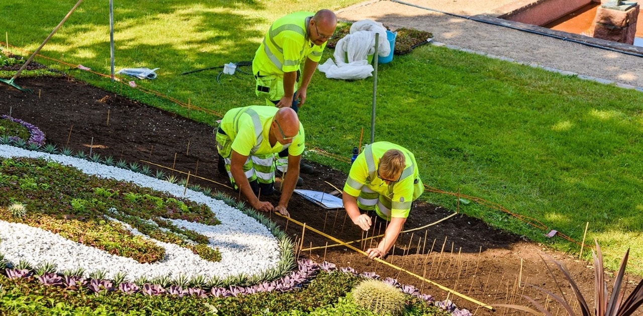 Three men in high-vis vests doing landscaping work