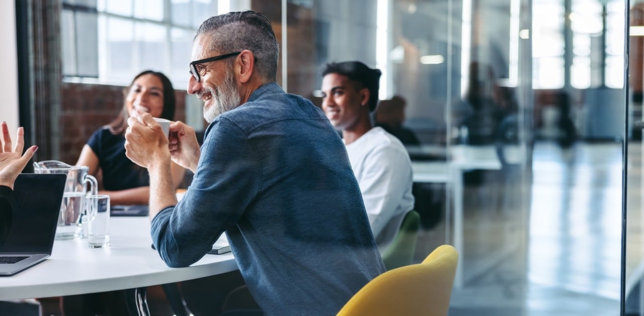 Smiling colleagues talking at conference table
