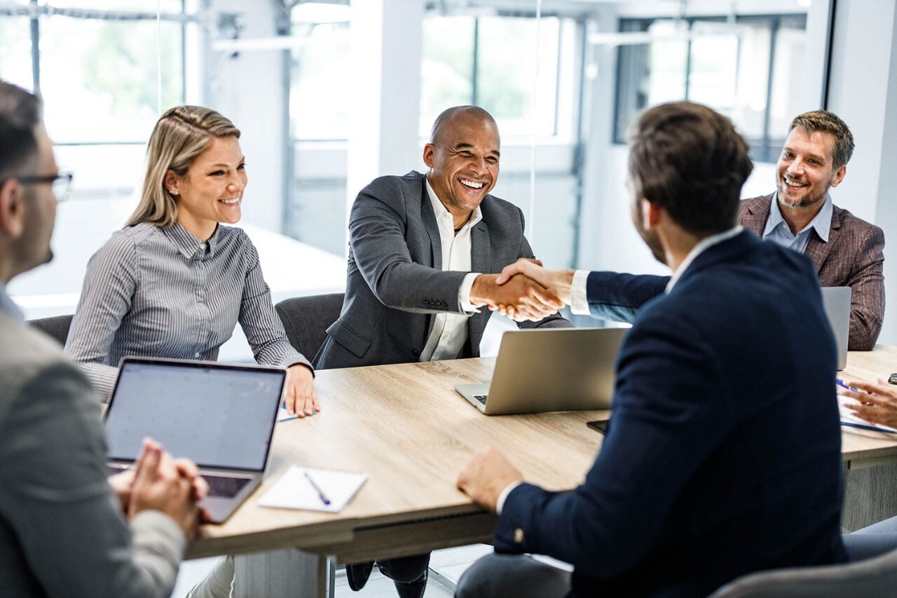 Smiling businesspeople meeting and shaking hands in conference room