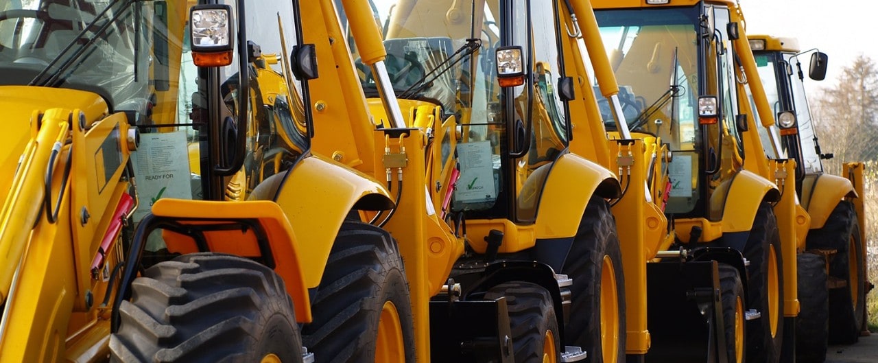 Several backhoe loaders in single-file line