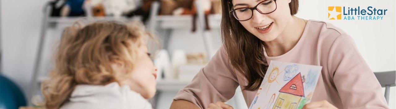 Woman and young girl looking at girl's drawing, with LittleStar ABA Therapy logo in corner