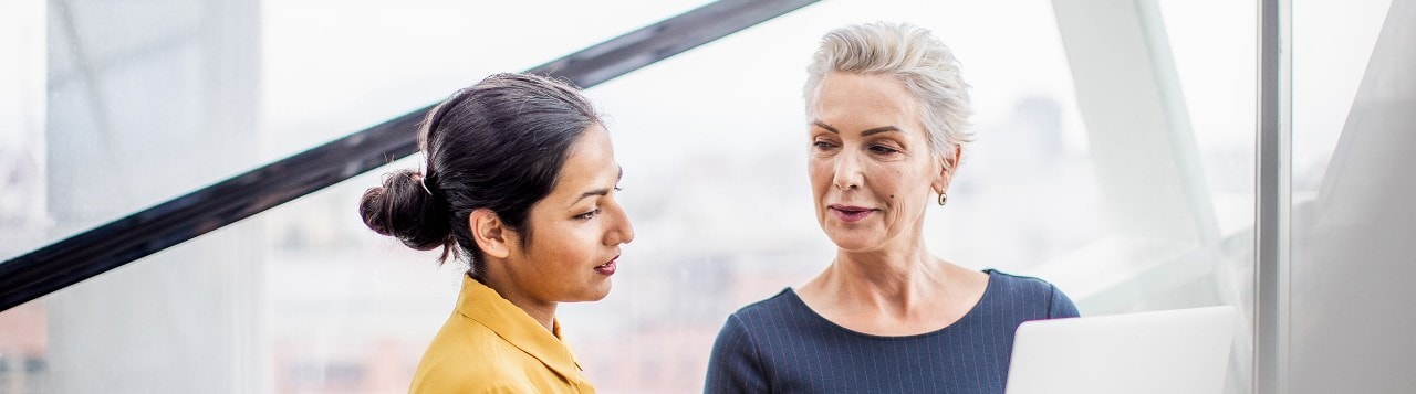 Two businesswomen reviewing information on a laptop