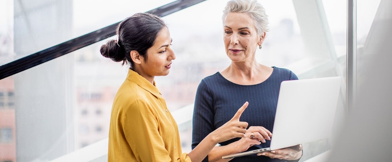 Two businesswomen reviewing information on a laptop