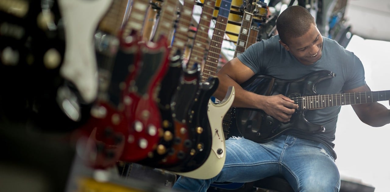 African-American man playing a guitar in a music store