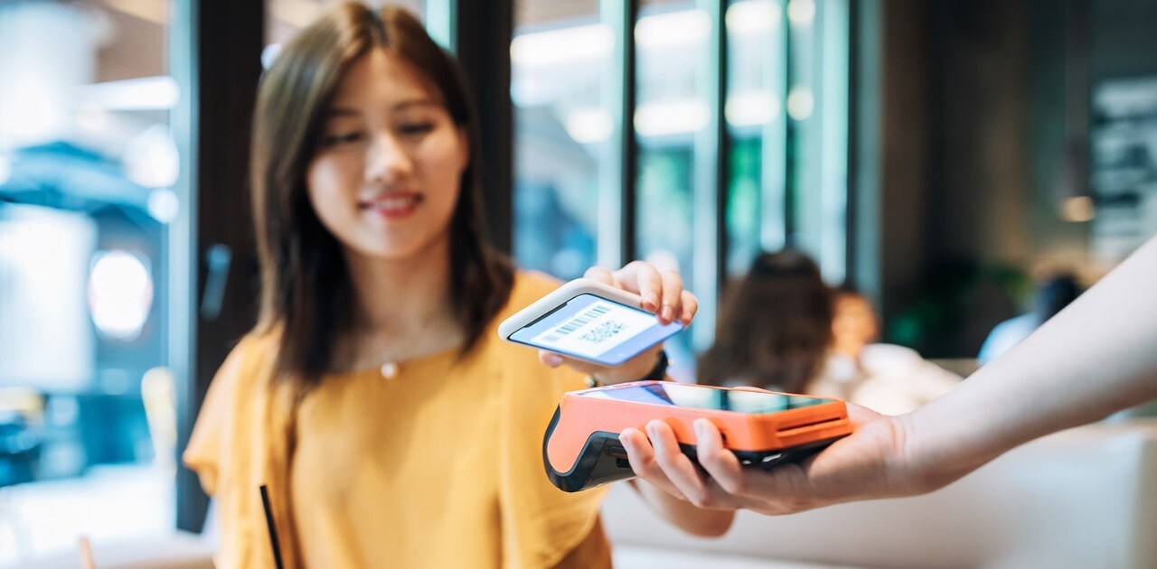 Young Asian-American woman using contactless payment with smartphone