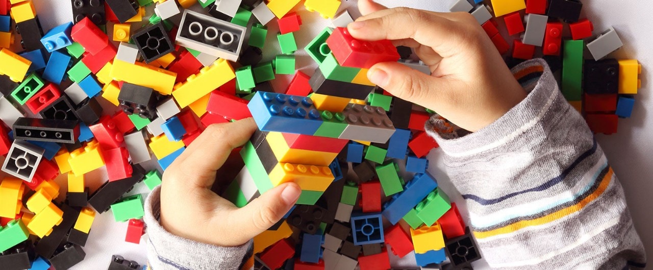 Close up of child's hand playing plastic toy building blocks