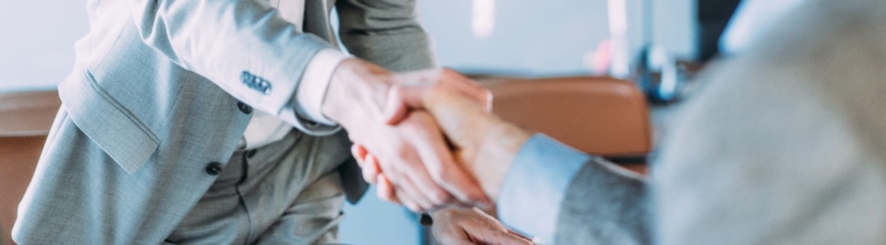 2 people shake hands while smiling