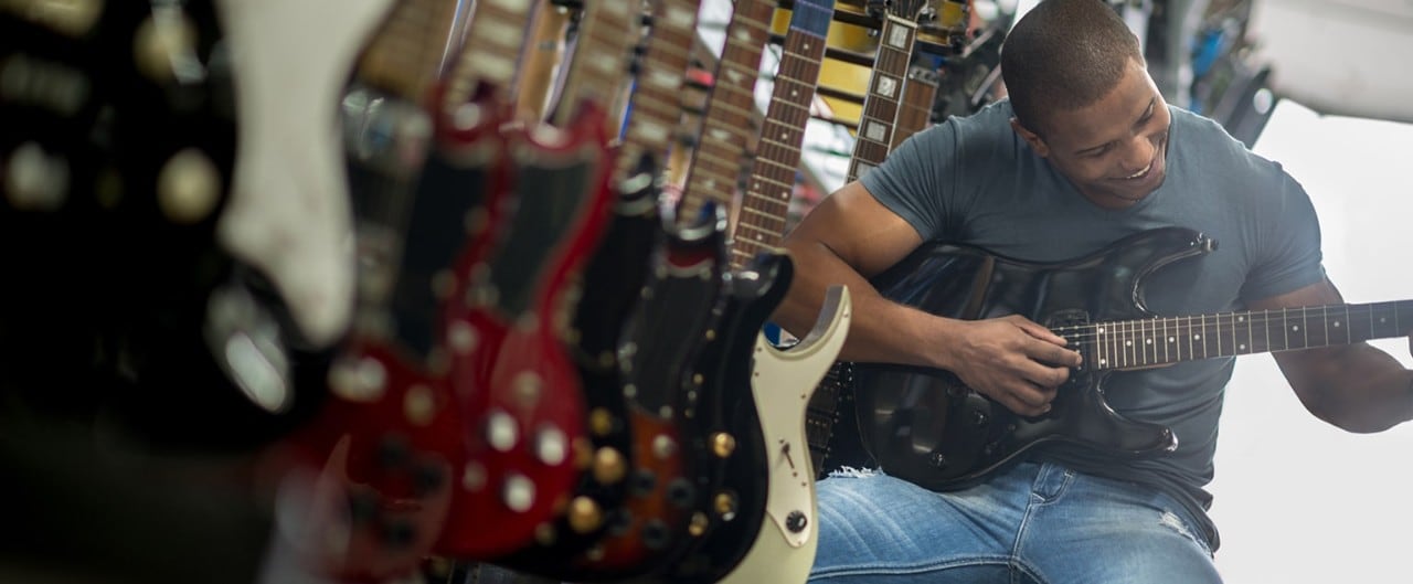 African-American man playing a guitar in a music store