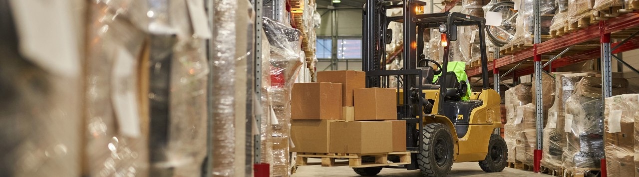 Forklift moving boxes in shipping warehouse