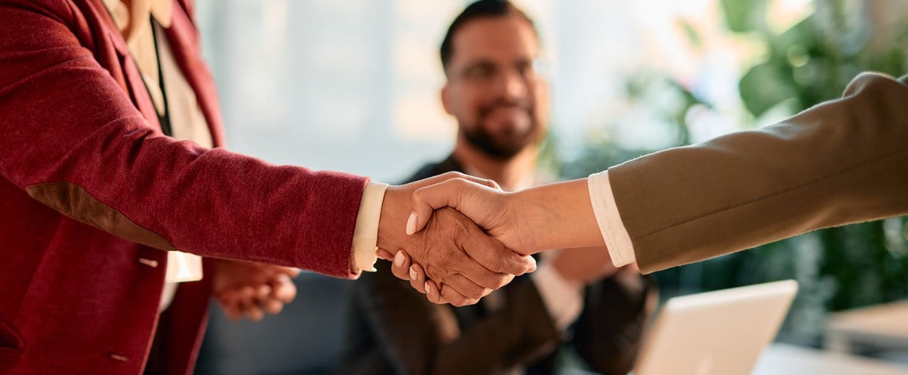 Two businesspeople shaking hands over a conference table