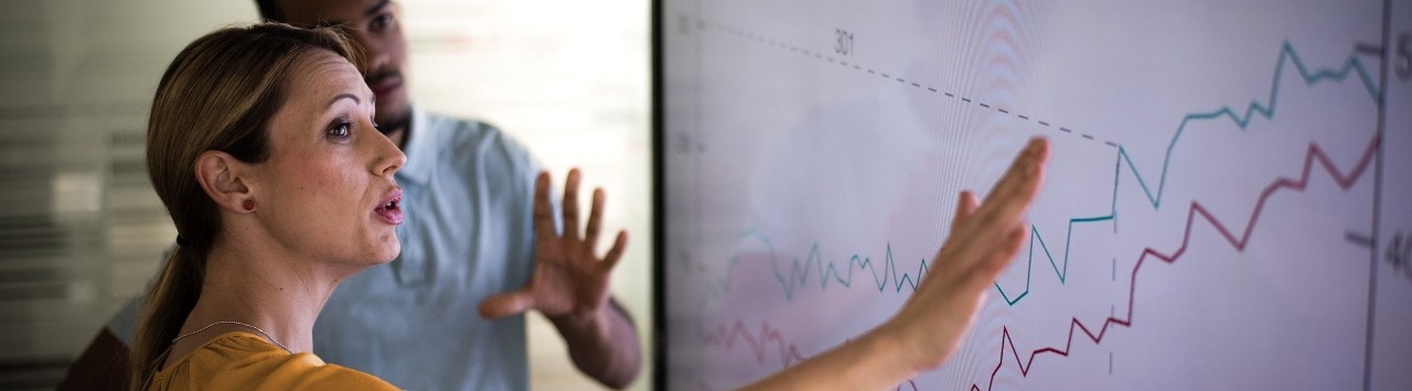 Female business owner showing employee profit tracking on large screen