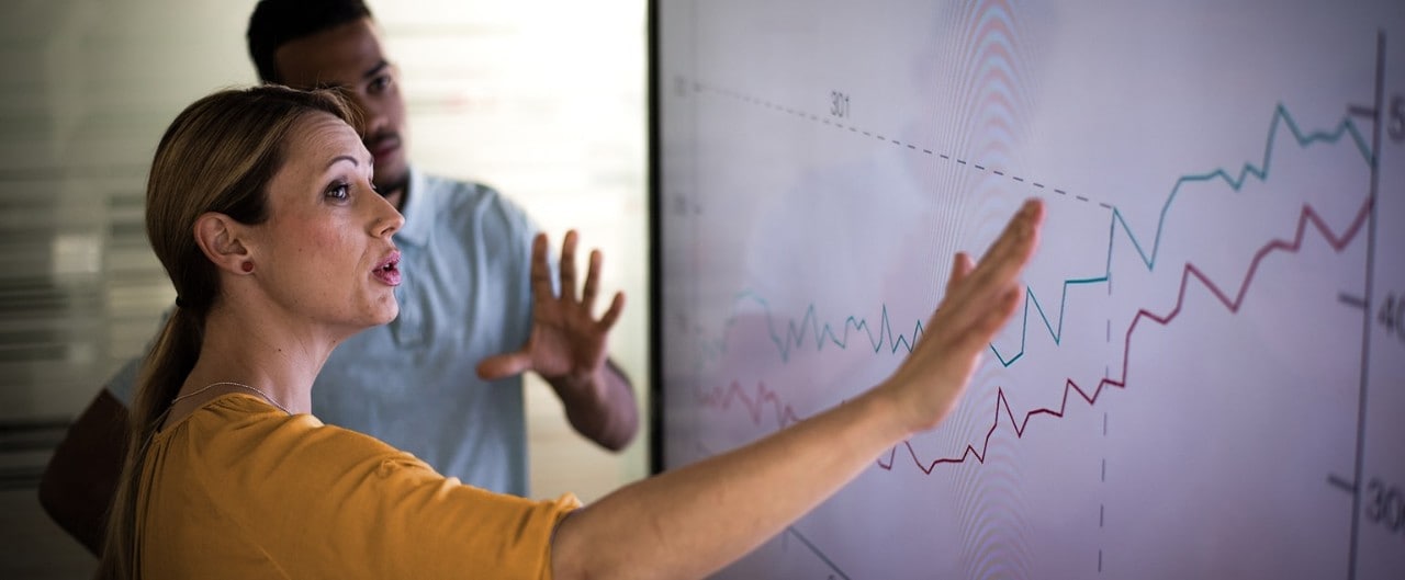 Female business owner showing employee profit tracking on large screen