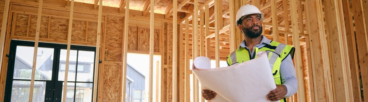 business owner holding blueprints at construction site