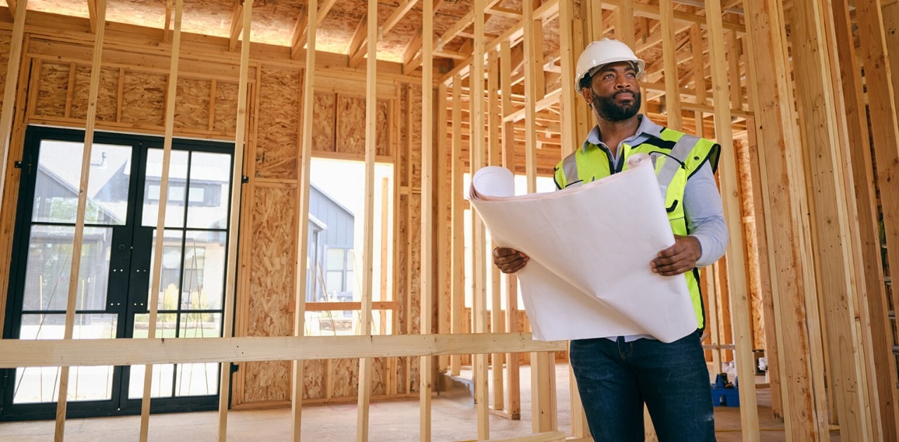 business owner holding blueprints at construction site